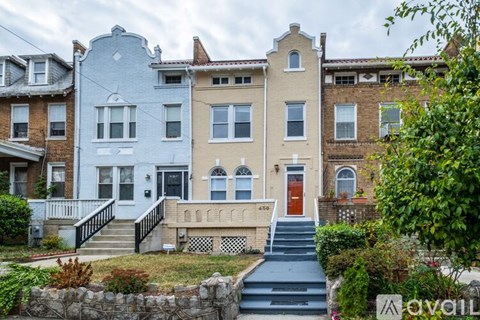A row of houses with a stone wall and steps leading to a red door.