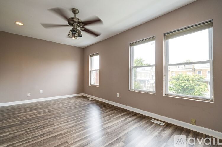 A spacious room with a ceiling fan and hardwood flooring.