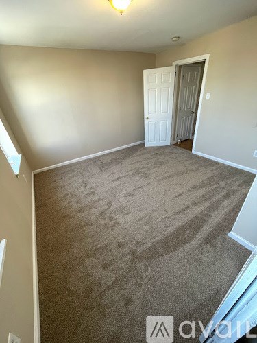 A room with a carpeted floor and a door.