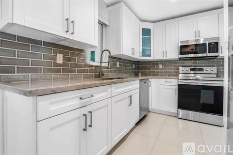 A kitchen with white cabinets and a brick backsplash.