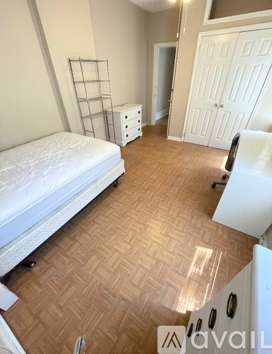 A bedroom with a white bed and wooden flooring.
