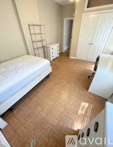 A bedroom with a white bed and wooden flooring.