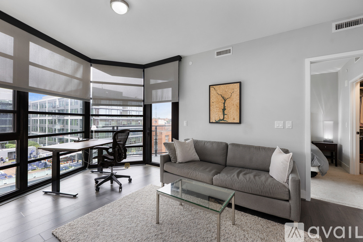 A living room with a grey couch and a glass table.