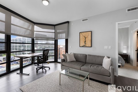 A living room with a grey couch and a glass table.