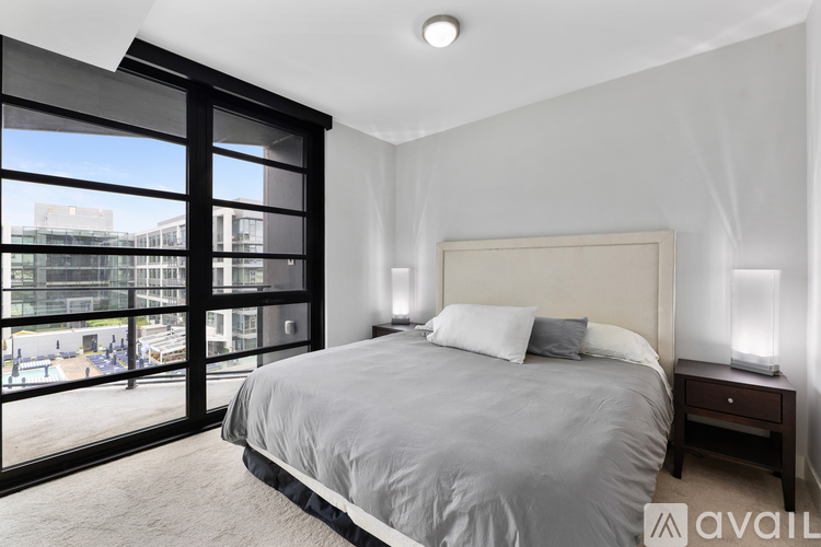 A bedroom with a large bed and a balcony with a view of the city.