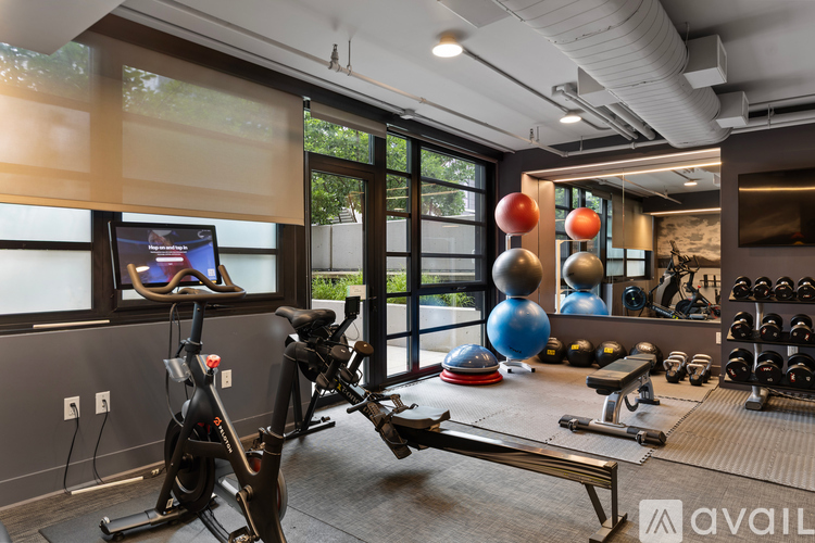 A gym with exercise equipment and a window overlooking a backyard.