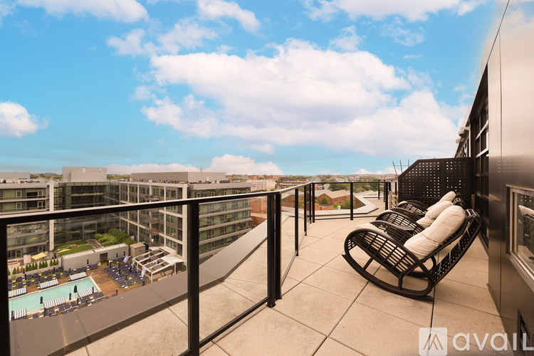 A balcony with a chair and a table overlooking a pool and buildings.