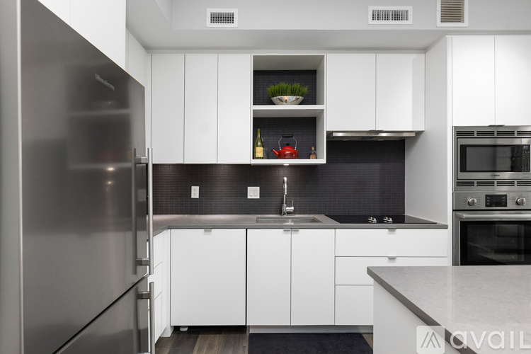 A modern kitchen with white cabinets and a stainless steel refrigerator.
