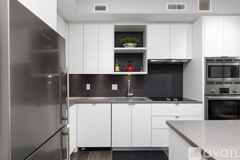 A modern kitchen with white cabinets and a stainless steel refrigerator.