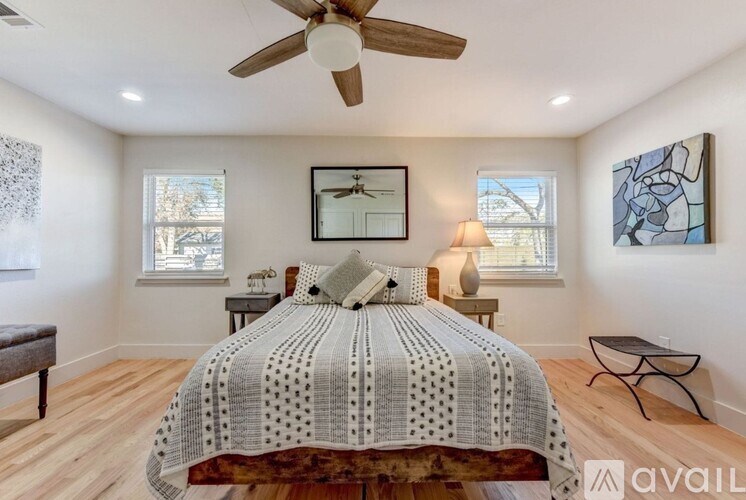 A bedroom with a bed in the center and a ceiling fan above it.