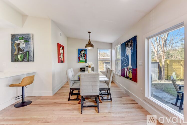 A dining room with a table set for four and a painting on the wall.