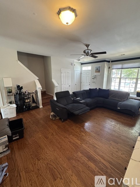 A living room with a black couch and a ceiling fan.