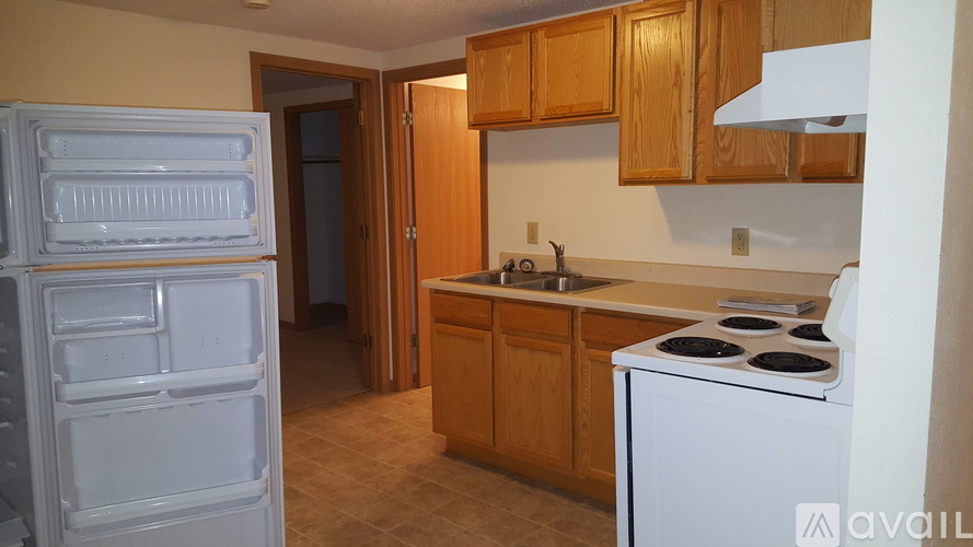 A kitchen with a white fridge and stove, wooden cabinets, and a tiled floor.