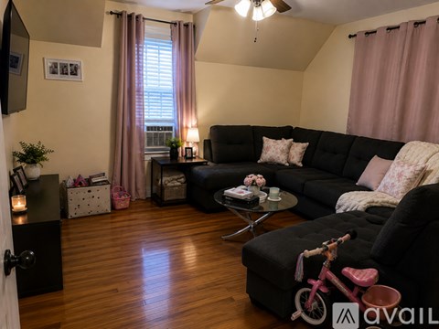 A living room with a black couch and a pink bicycle.