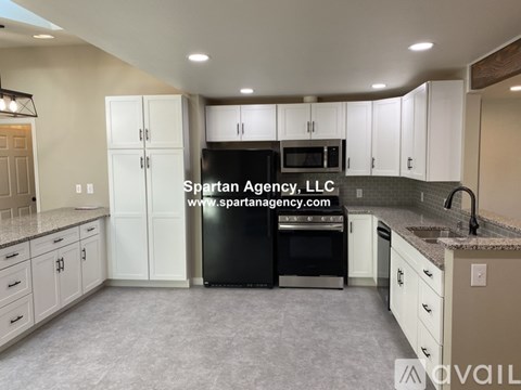 A kitchen with white cabinets and a black dishwasher.