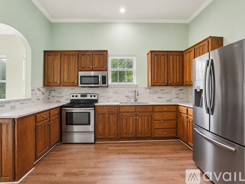 A kitchen with wooden cabinets and a stainless steel refrigerator.
