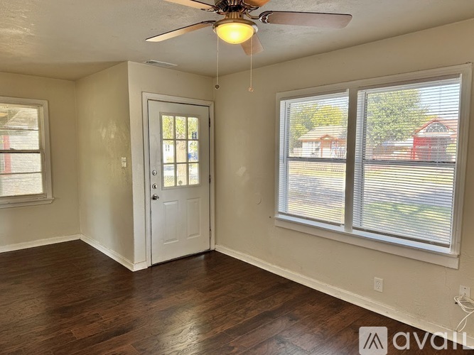 A room with a ceiling fan and two windows.