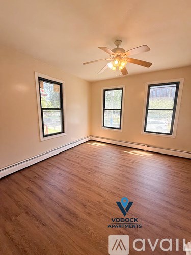 A room with wooden flooring and a ceiling fan.