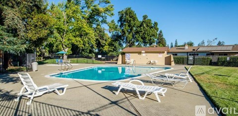 A pool surrounded by lawn chairs and trees.