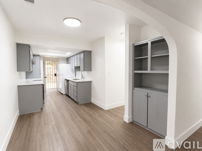 A spacious kitchen with grey cabinets and a light brown floor.