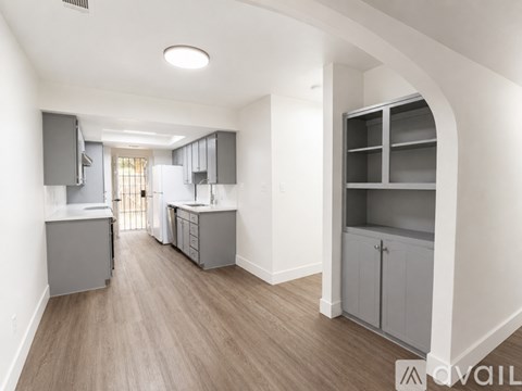 A spacious kitchen with grey cabinets and a light brown floor.