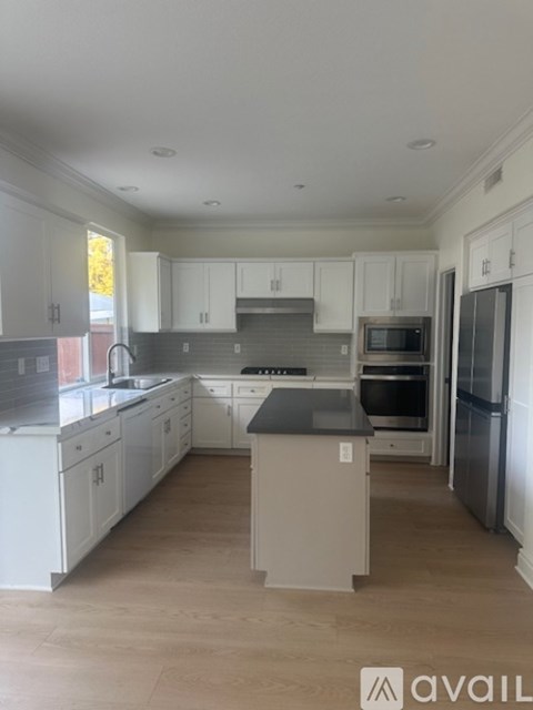 A kitchen with white cabinets and a grey island.