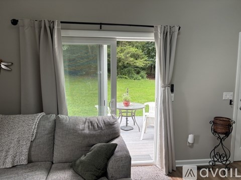 A living room with a grey couch and a table outside.