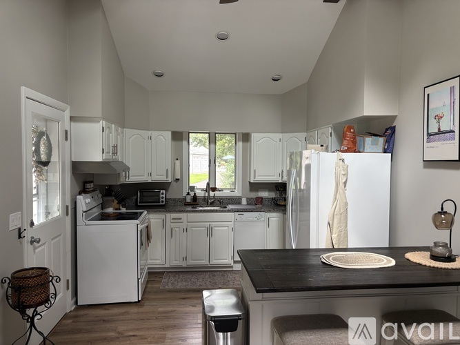 A kitchen with white appliances and a black countertop.