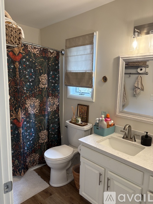 A bathroom with a floral shower curtain and a white toilet.