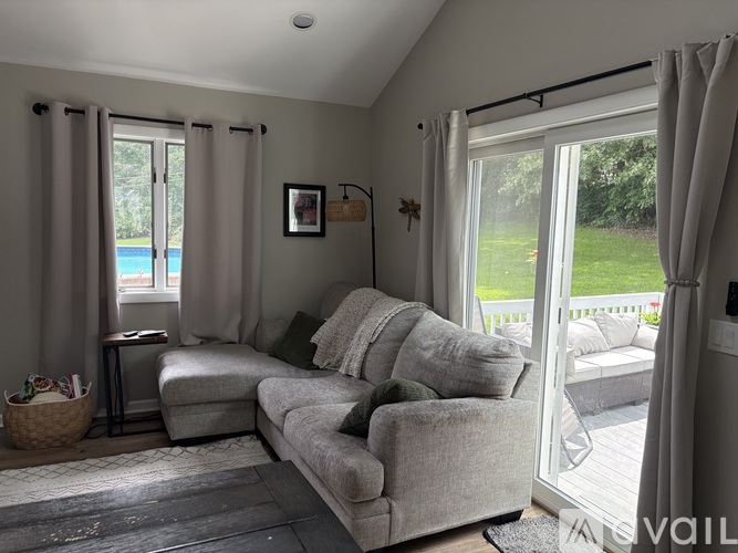 A living room with a grey couch and a window with curtains.