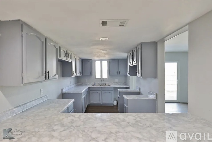 A kitchen with grey cabinets and a marble countertop.