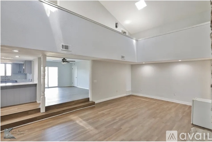 A spacious room with wooden flooring and white walls.