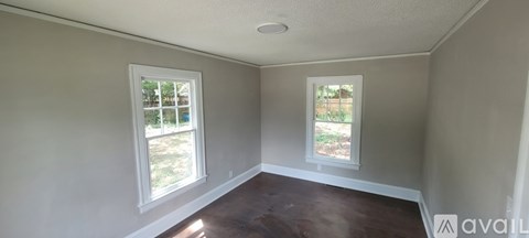 A room with two windows and a wooden floor.