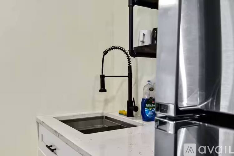 A kitchen sink with a faucet and a bottle of cleaning liquid on the counter.
