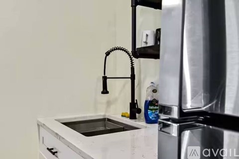 A kitchen sink with a faucet and a bottle of cleaning liquid on the counter.