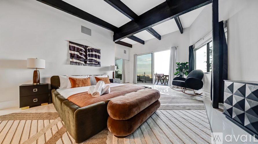 A bedroom with a large bed and a chair.