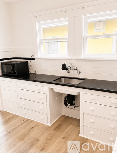 A kitchen with white cabinets and a black countertop.