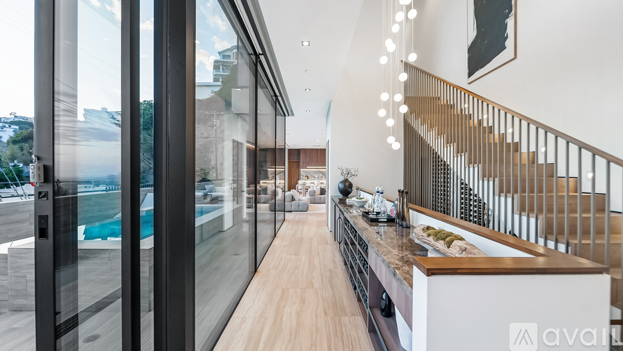 A modern kitchen with a glass wall and a staircase.
