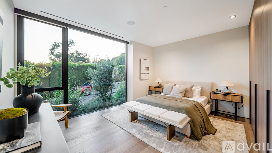 A bedroom with a large bed and a view of the outdoors through the window.