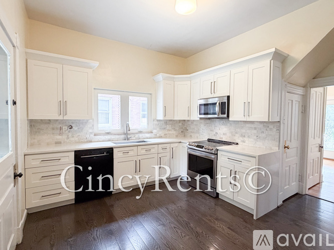 A kitchen with white cabinets and a wooden floor.