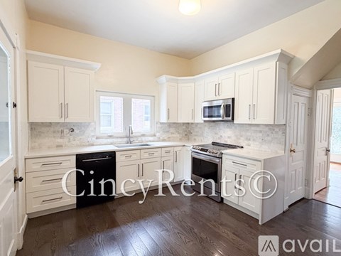 A kitchen with white cabinets and a wooden floor.