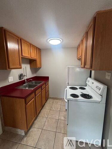 A kitchen with a white stove and wooden cabinets.