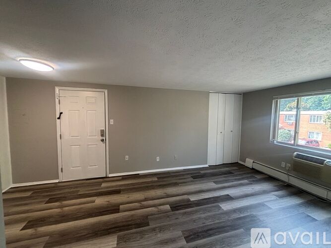 A room with a white door and a window with a view of a building outside.