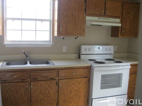 A kitchen with a white stove and wooden cabinets.