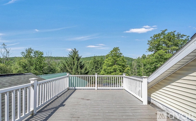 A deck with white railings overlooks a forested area.