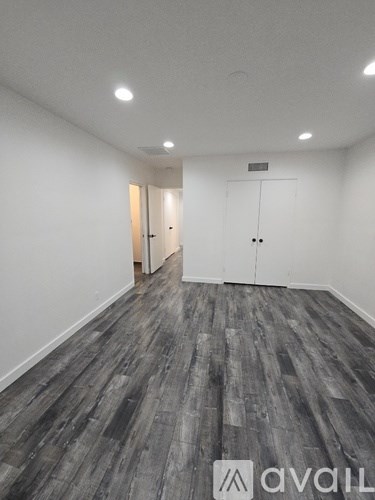 A room with wooden flooring and white walls.