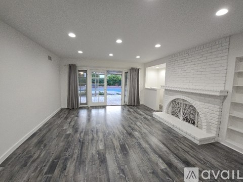 A spacious room with a fireplace and wood flooring.