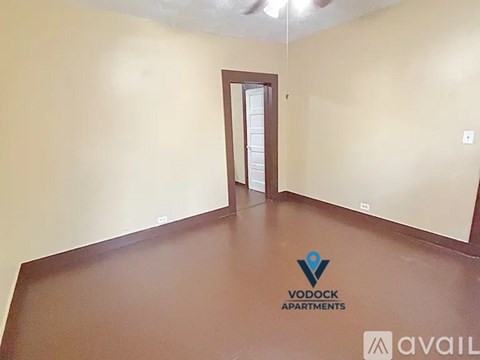 A spacious room with a door and a logo of Vodock Apartments on the floor.