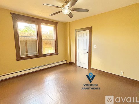 A room with a ceiling fan and a window with a view of a tree.