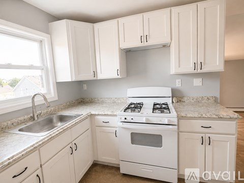 A kitchen with white cabinets and appliances.